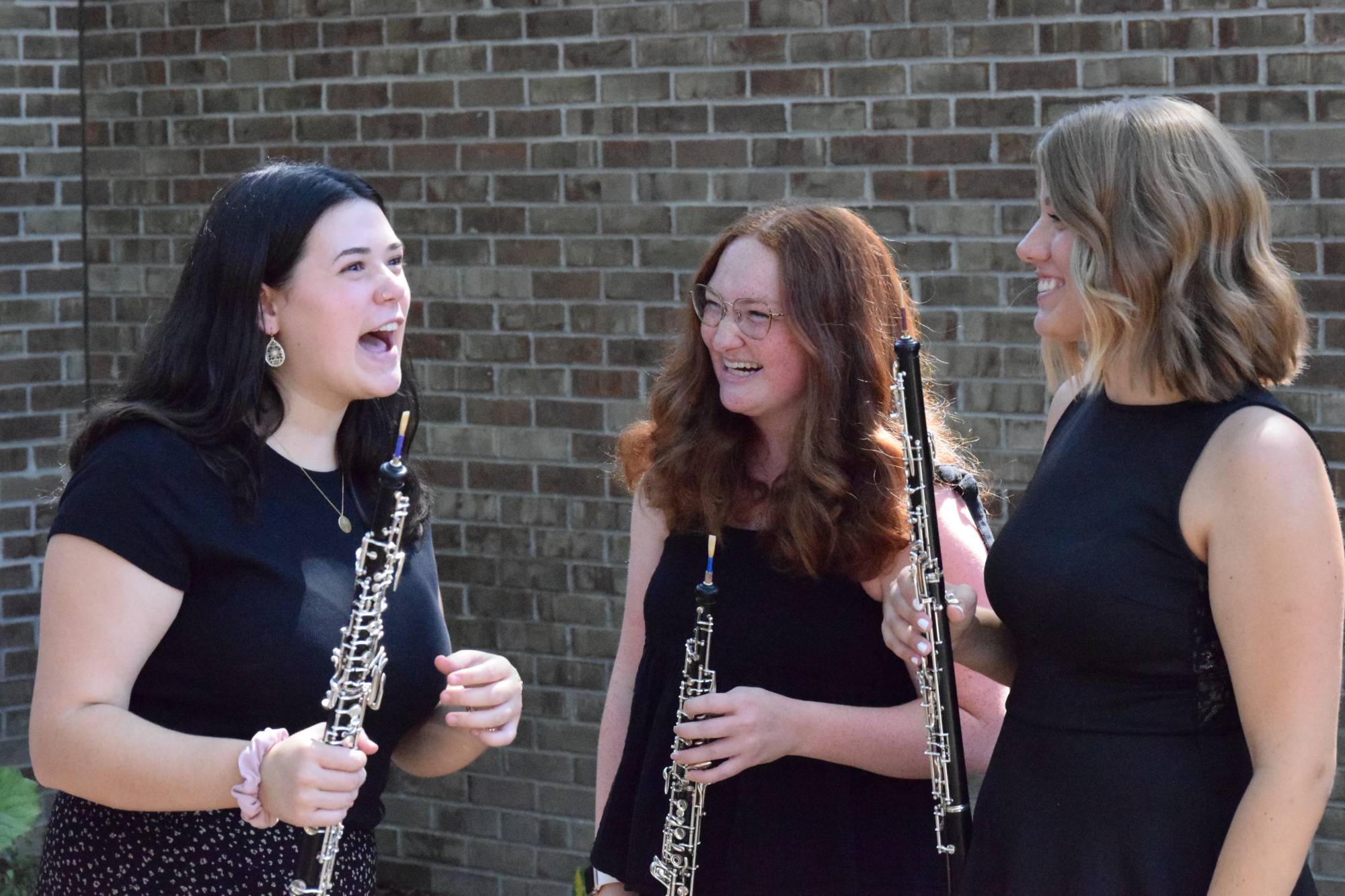 Lea Carter, Natalie Kline, and Natalie Feldpausch holding their oboes in the Marcia Haas garden at HCPA.
